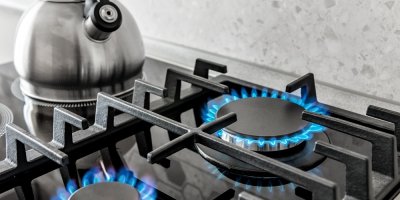 Plynový sporák s modrými plameny a šedou konvicí