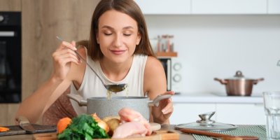 Žena ochutnává vývar z hrnce