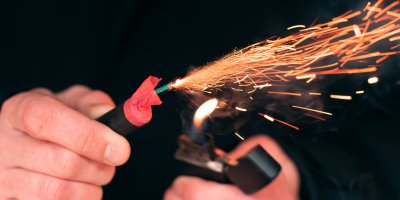 Muž v rukou zapaluje petardu