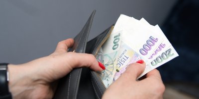 Žena s červenými nehty vytahuje české bankovky z peněženky