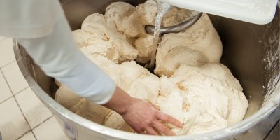 Pekař připravuje syrové těsto v míse
