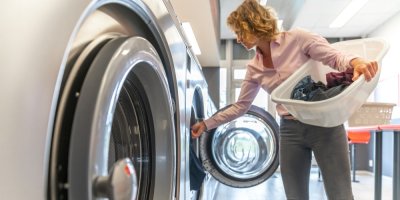 Žena vkládá prádlo do pračky ve veřejné prádelně