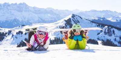 Dvě ženy oblečené do lyžařského leží na sněhu