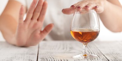 Člověk přikrývá dlaní sklenici s vínem a druhou rukou naznačuje odmítnutí