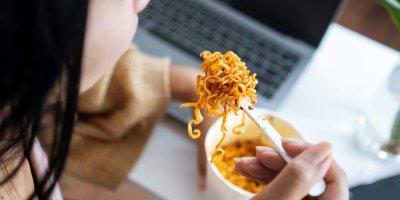 Žena jí u počítače instantní nudle