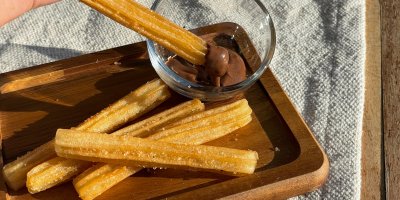 Domácí churros s čokoládovým dipem na dřevěném prkénku