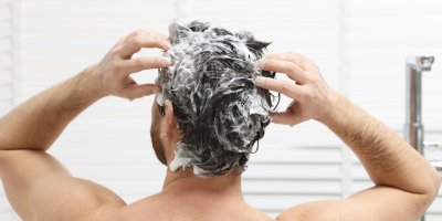 Muž si myje vlasy šamponem