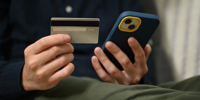 Muž drží v rukou platební kartu a mobil