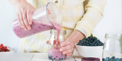 Člověk přelévá borůvkové smoothie z mixéru do sklenice