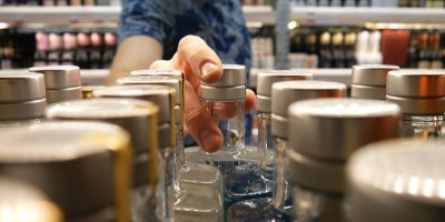 Muž si v obchodě bere jednu z lahví tvrdého alkoholu