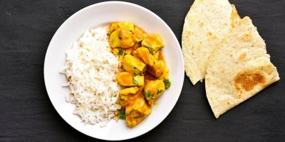 Kuřecí kari s rýží v bílé misce a chlebová placka