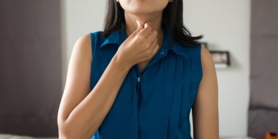 Žena se prsty dotýká svého krku