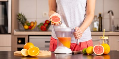 Žena připravuje šťávu z grapefruitu a citrusů
