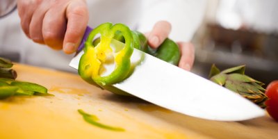 Kuchyňský nůž krájí zelenou papriku