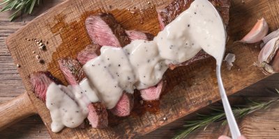 Kuchař polévá steaky pepřovou omáčkou