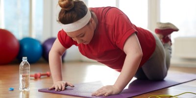 Žena provádí dámský klik na cvičební podložce. 