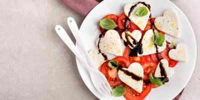 Caprese se sýrem ve tvaru srdce na bílém talíři