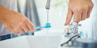 Na kartáček s pastou teče voda z kohoutku