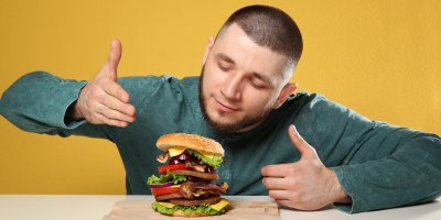 Muž ukazuje na burger