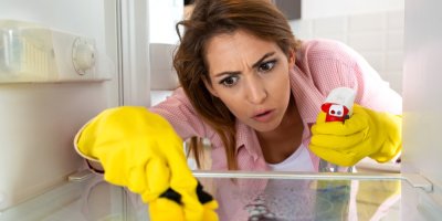 Žena v rukavicích  čistí ledničku