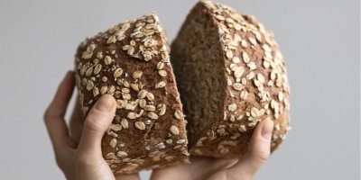 Člověk drží rozkrojený tmavý chléb