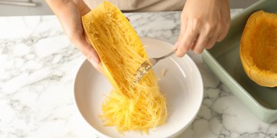 Žena servíruje na talíř špagetovou dýni