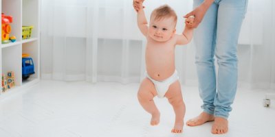 Malé dítě se učí chodit, matka jej drží za ruce