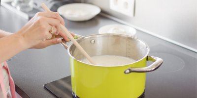 Míchání mléka ve žlutém hrnci