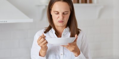 Žena se znechuceně dívá do talíře