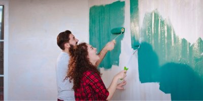 Mladý muž a žena malují zeď modrozelenou barvou