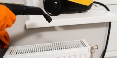 Člověk čistí radiátor parním čističem