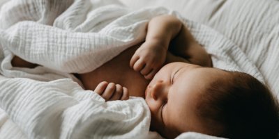 Dítě spí přikryté mušelínovou látkou