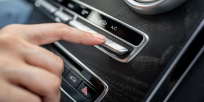 Žena zapíná v autě klimatizaci