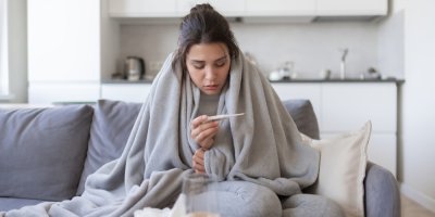 Nemocná mladá žena si měří teplotu