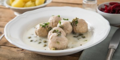 Masové knedlíčky na bílém talíři s omáčkou