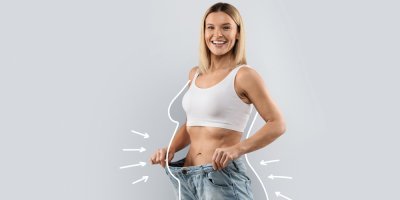 Usmívající se žena ukazuje svou štíhlou postavu po hubnoucí proceduře