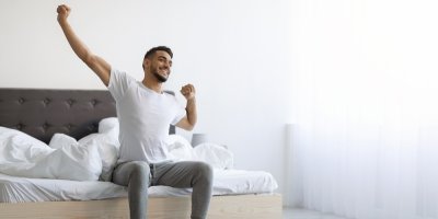 Mladý usmívající se muž vstává z postele