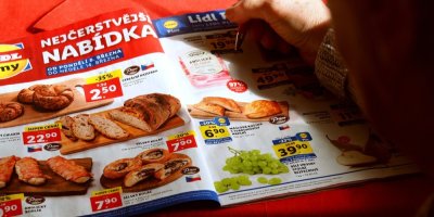Člověk kroužkuje ceny v letáku Lidlu