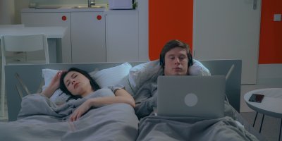 Žena spí, zatímco muž pracuje na počítači