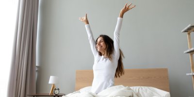 Veselá žena sedí na posteli