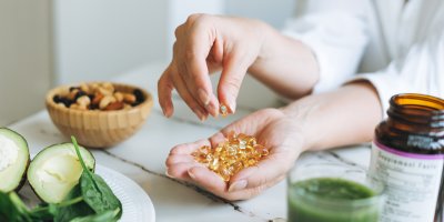 Žena má v dlani mnoho vitamínových kapslí