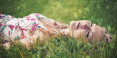 Žena leží v trávě se zavřenýma očima