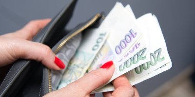 Žena drží v rukou peněženku s českými bankovkami