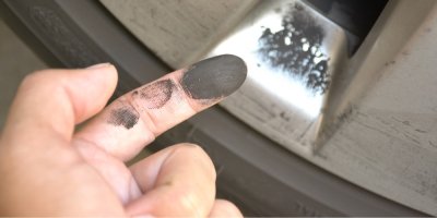 Prach z brzdových destiček na prstu a na ráfku