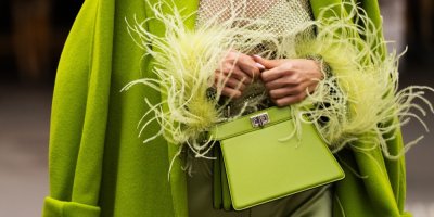 Žena oblečená v zeleném kabátku a se zelenou kabelkou