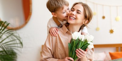 Žena drží tulipány v ruce a za ní stojí chlapec