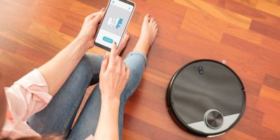 Žena ovládá robotický vysavač přes mobilní aplikaci