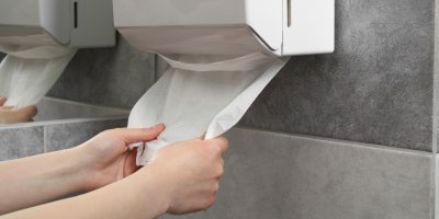 Žena vytahuje papírovou utěrku na toaletě