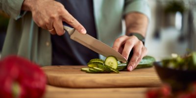 Muž krájí ostrým nožem okurku