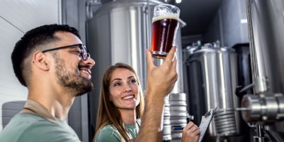 Muž a žena v pivovaru zkoumají pivo ve sklenici